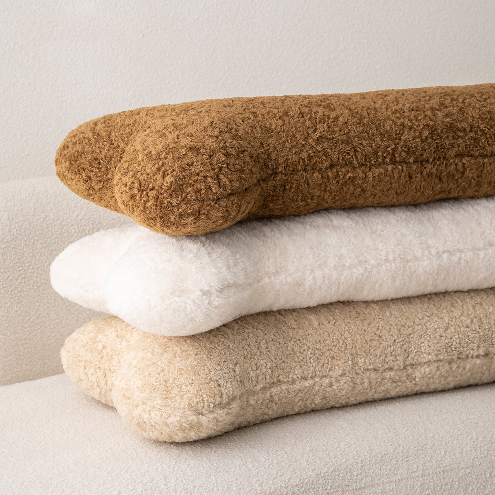 Three bone pillows stacked — caramel, white, and beige